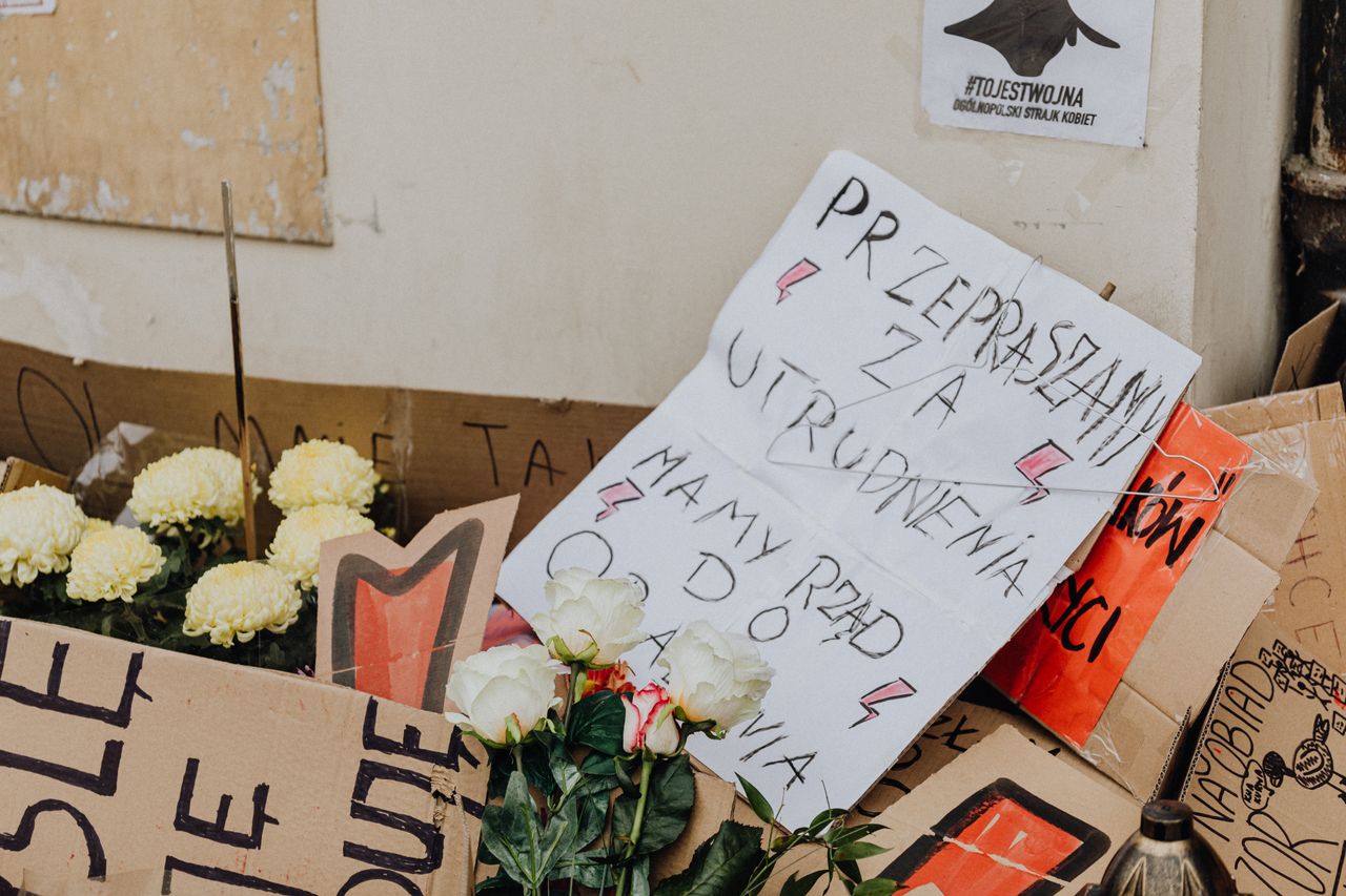 Cardboard protest signs and flowers at a demonstration in Poland.